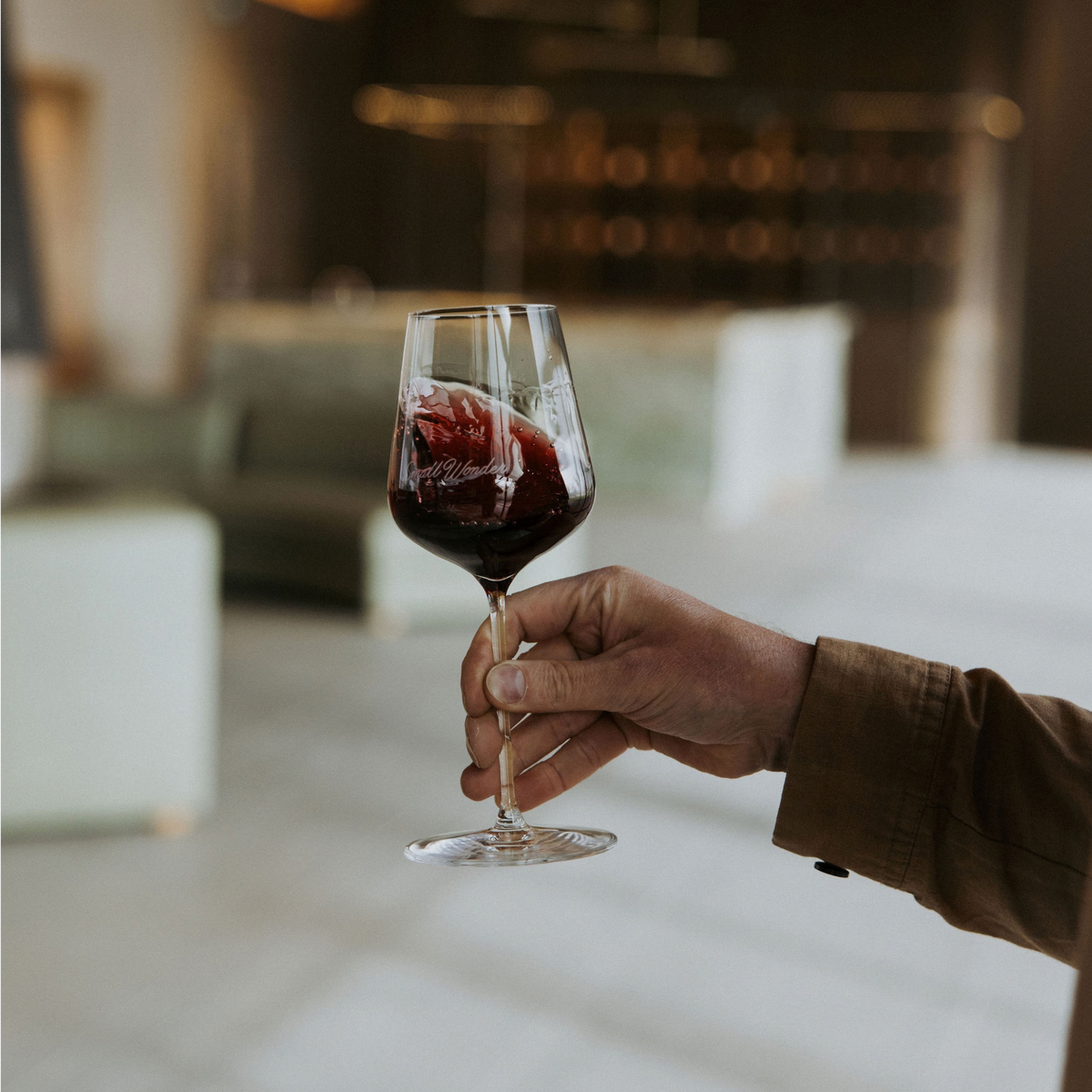 someone holding glass of red wine and swirling before taking a sip